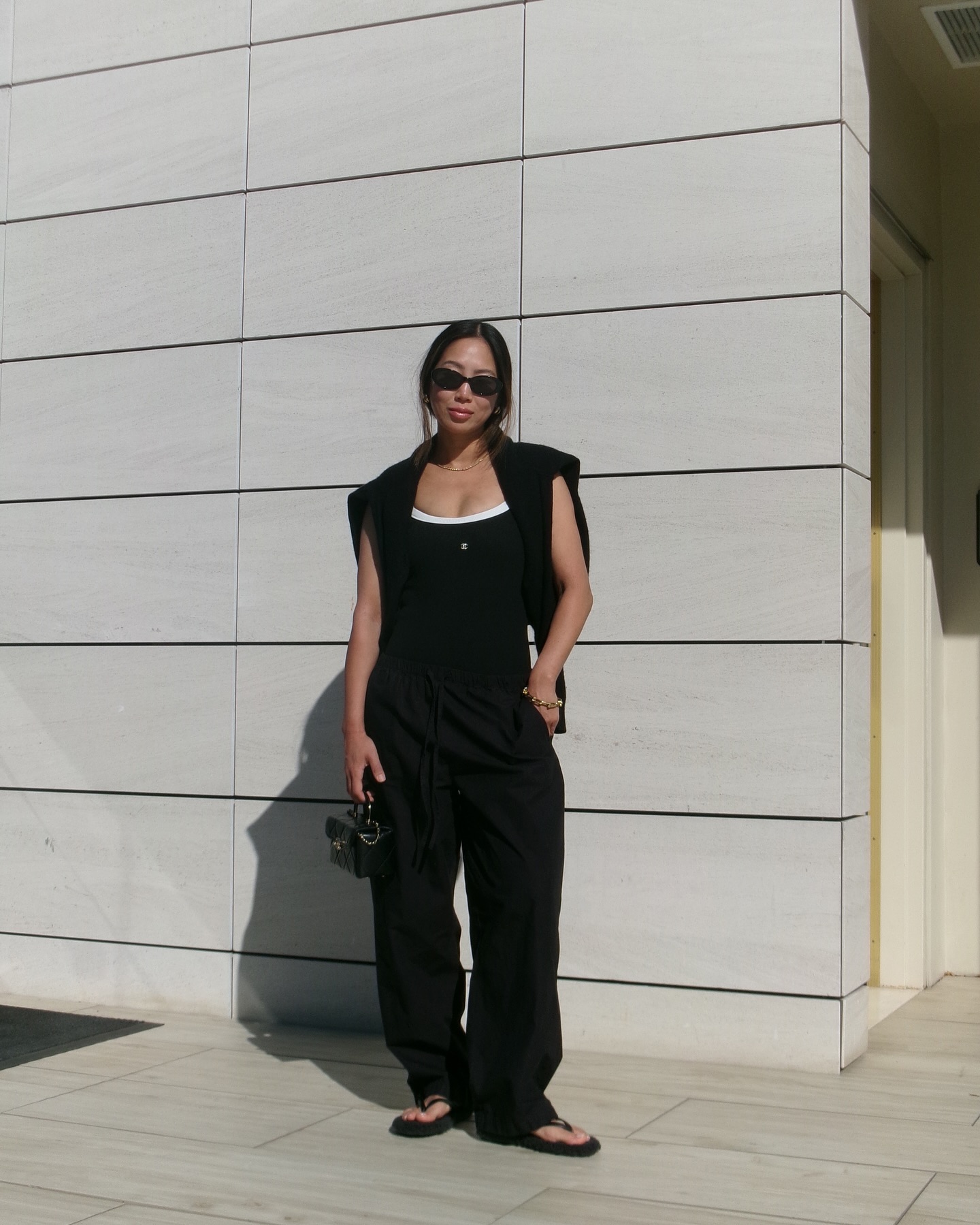 Aimee wears a black top, black pants, black flip flops.