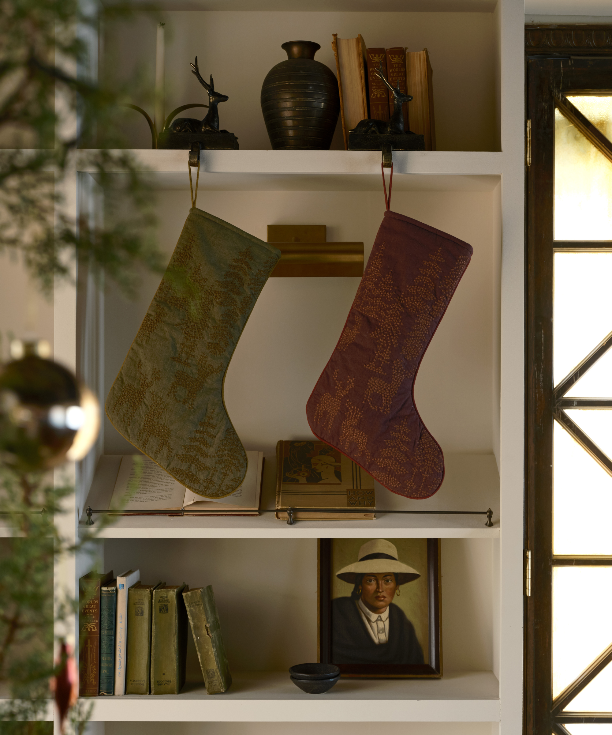 two stockings hanging from a bookcase with books and various decor