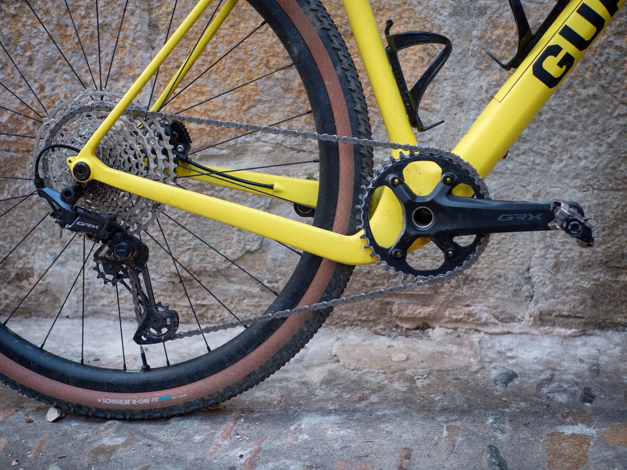 A yellow Guava Spot gravel bike leans against a wall