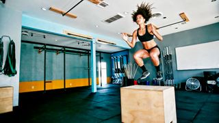 Woman performing box jump exercise in gym