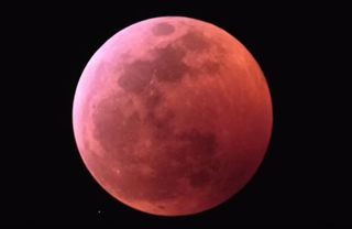 In a time-lapse video, photographer Jonathan Talbot captured the total lunar eclipse on Jan. 20 to 21, 2019. This still from the video depicts the moon completely enveloped by the darkest part of Earth's shadow, the umbra. In the bottom left, you can see a small meteor headed toward the moon.