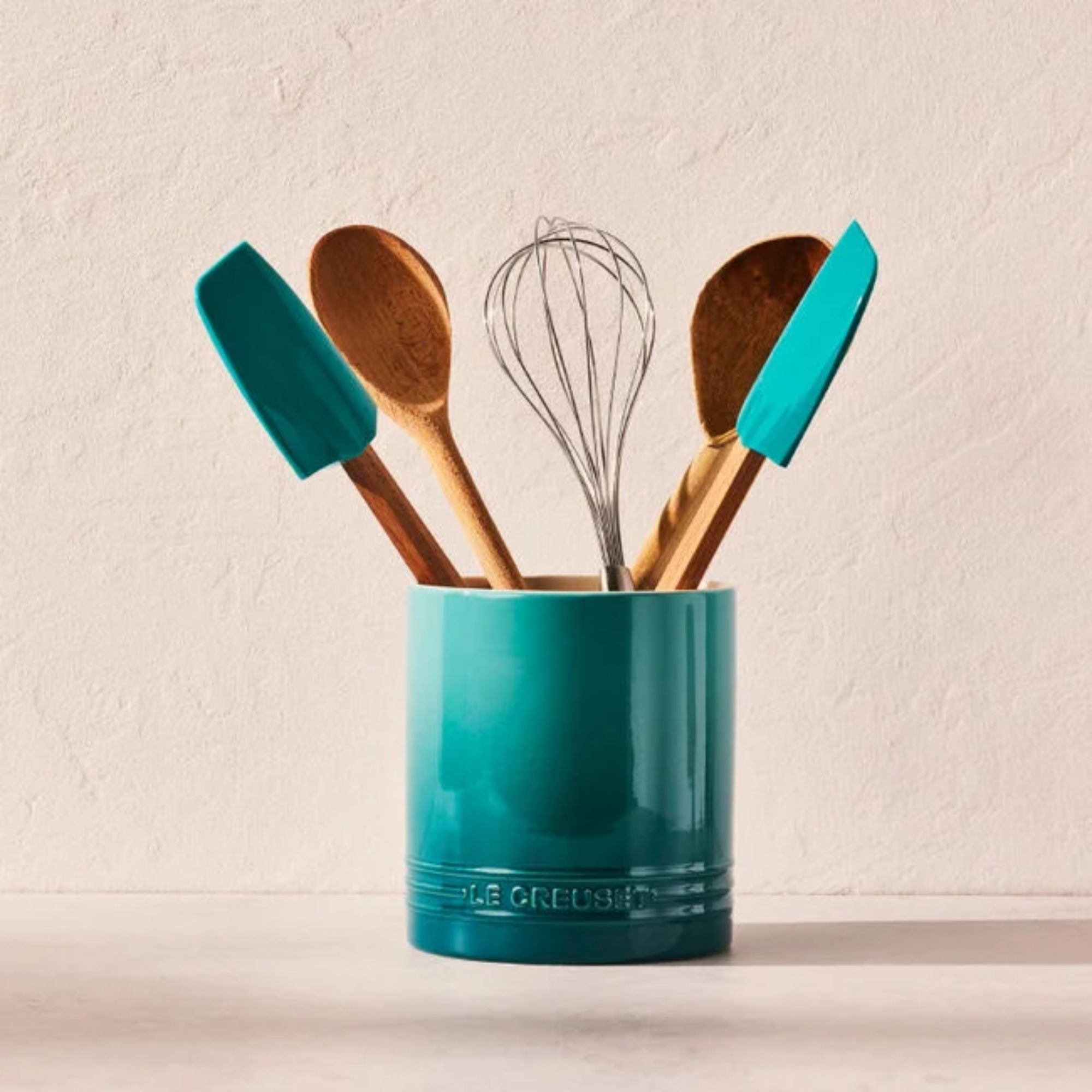A blue gradient utensil pot with wooden utensils inside it.