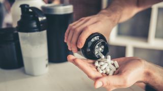 Supplement capsules being poured from jar into a hand