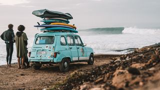 Two surfers with a car loaded with surf boards looking at the waves in Morocco