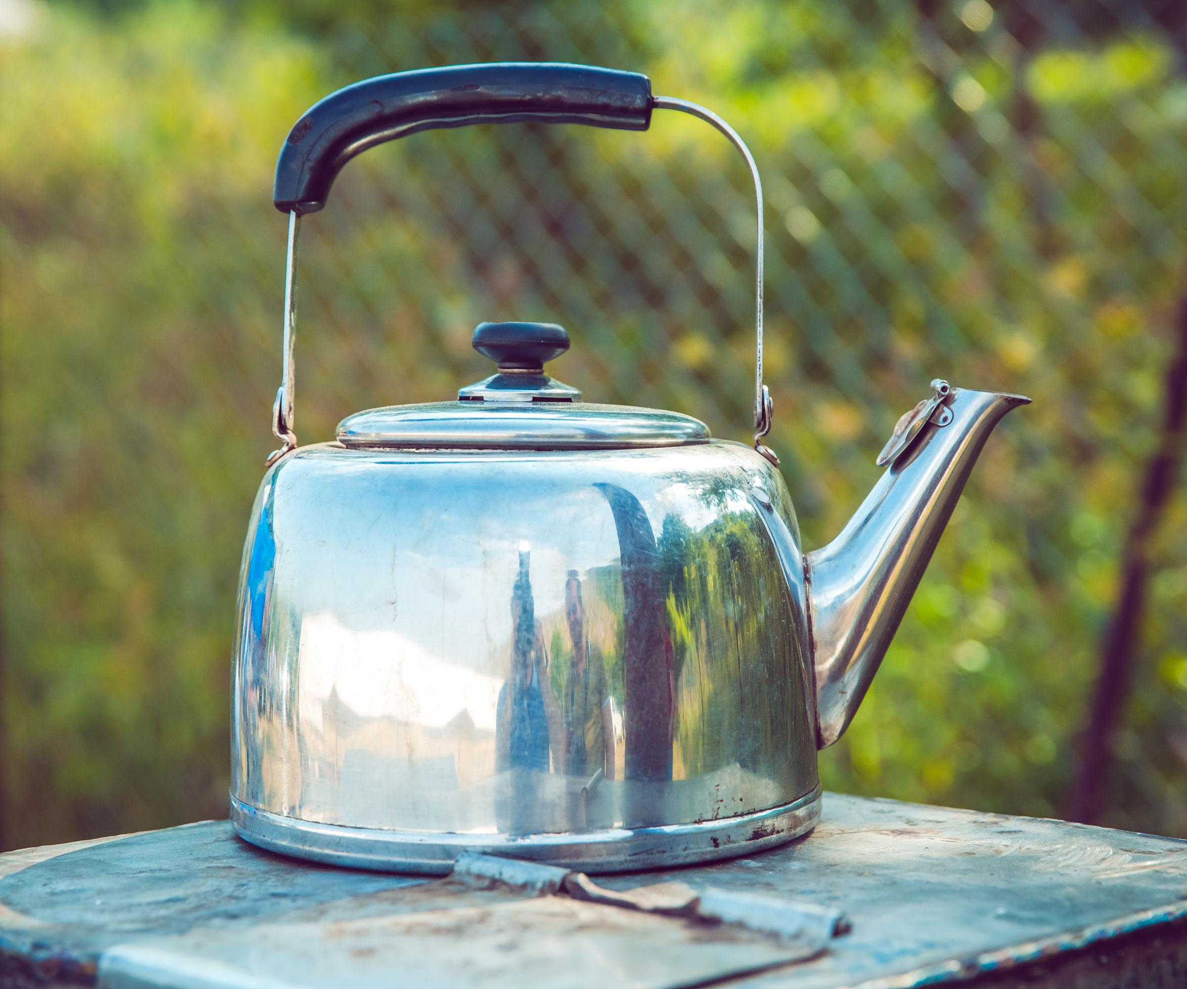 silver kettle on table in back garden near fence