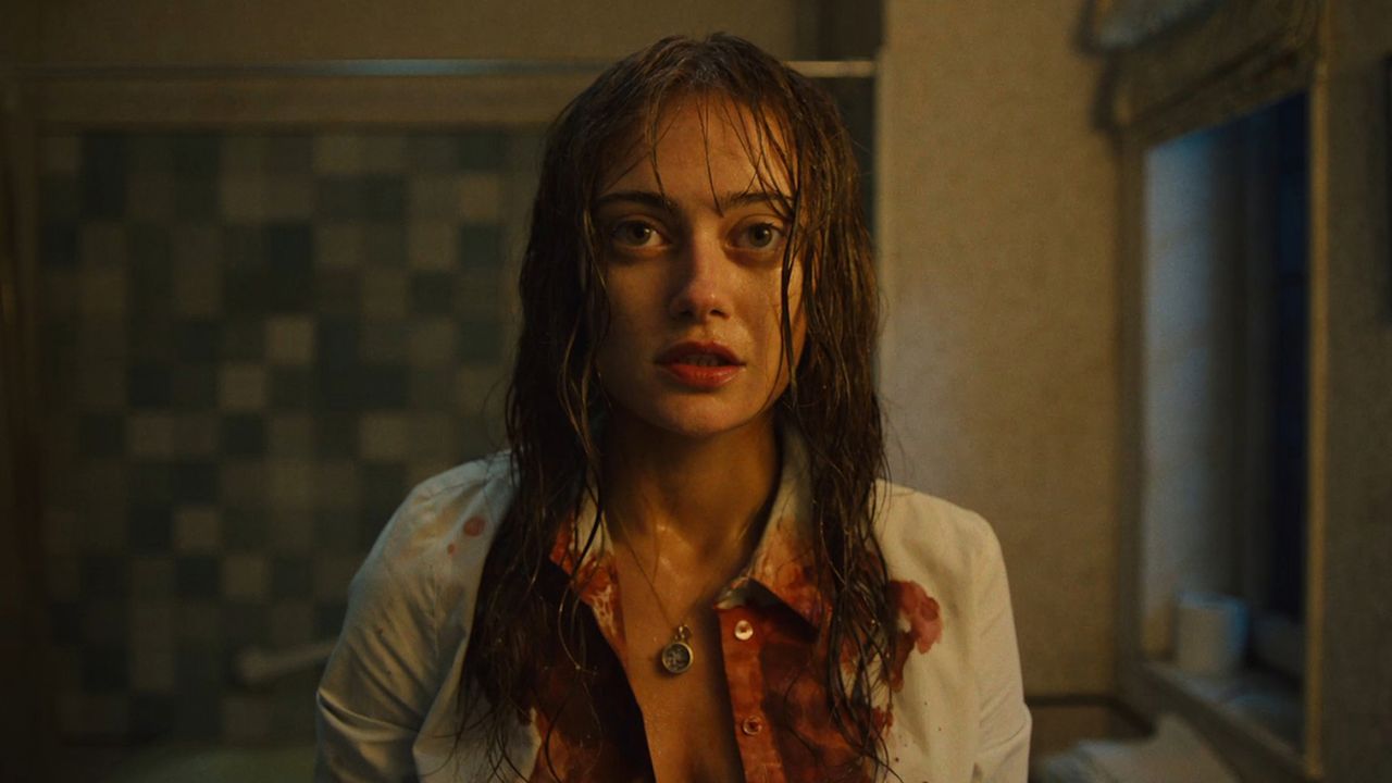 ella purnell as rhiannon in sweetpea looking into the mirror with blood on her shirt