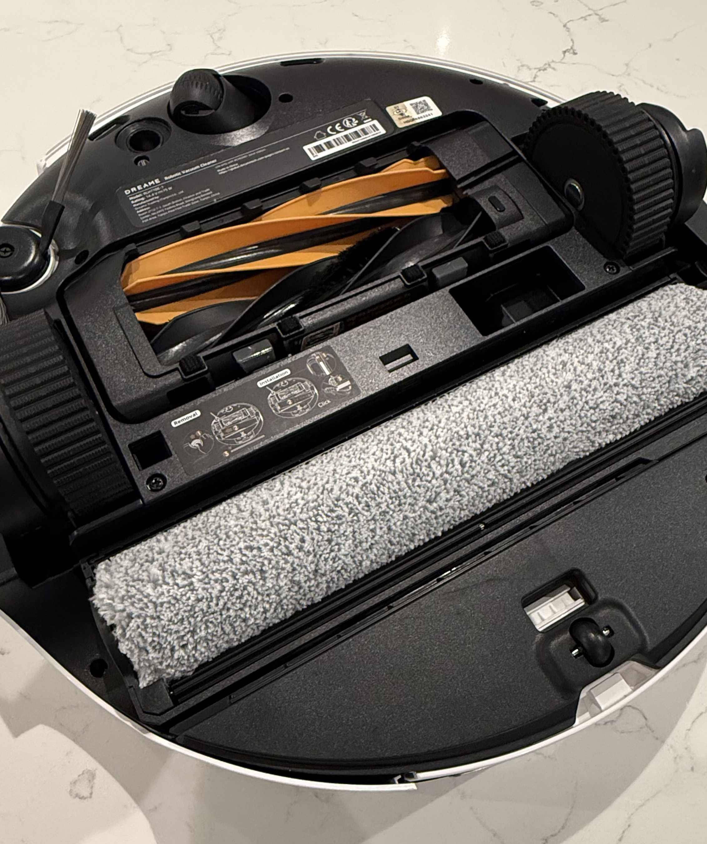 Underside of the Dreame Aqua10 Ultra Roller showing the main brush, side brush, wheels, and roller mop