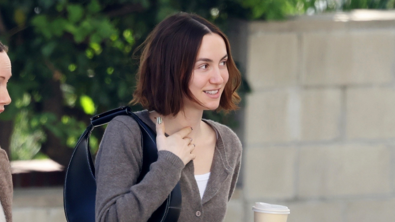 Maude Apatow wearing a brown Reformation cardigan, jeans, and black sneakers