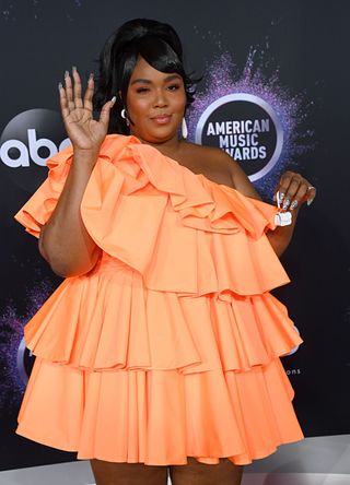 Lizzo wearing a ruffled orange gown with a tiny purse