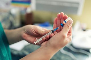 Person administering Covid-19 vaccine