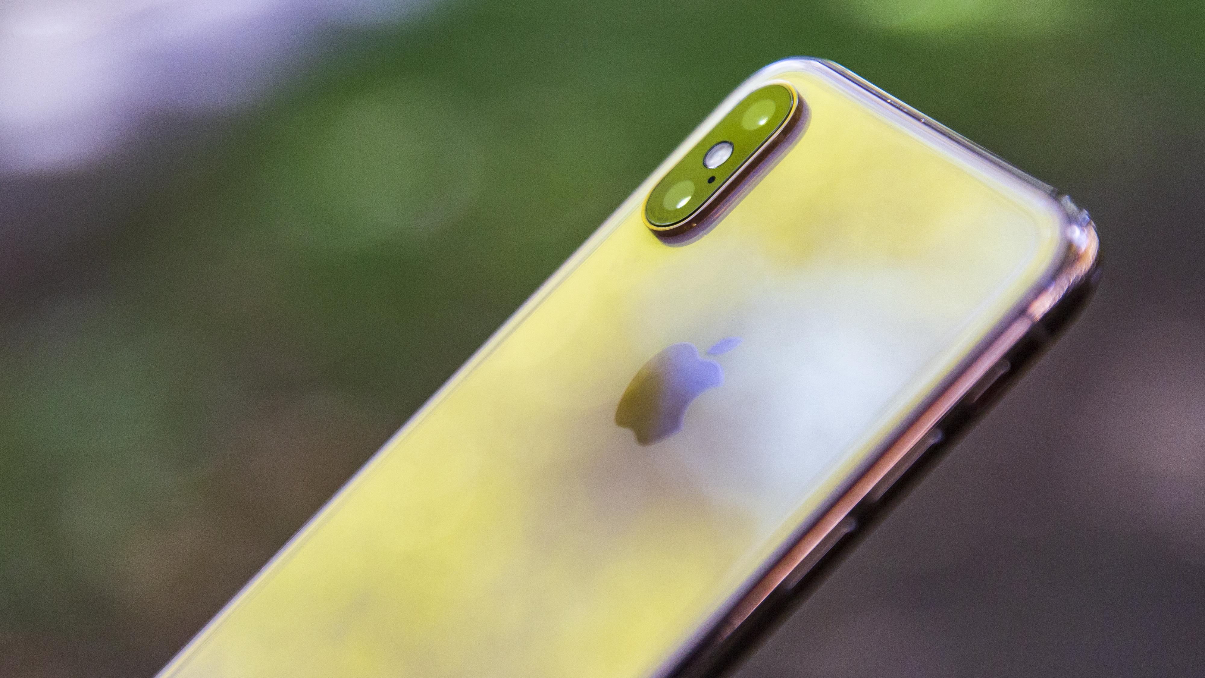 The iPhone Xs against a bokeh outdoor background