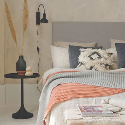 A scandi-style bedroom with layered bedding and cushions