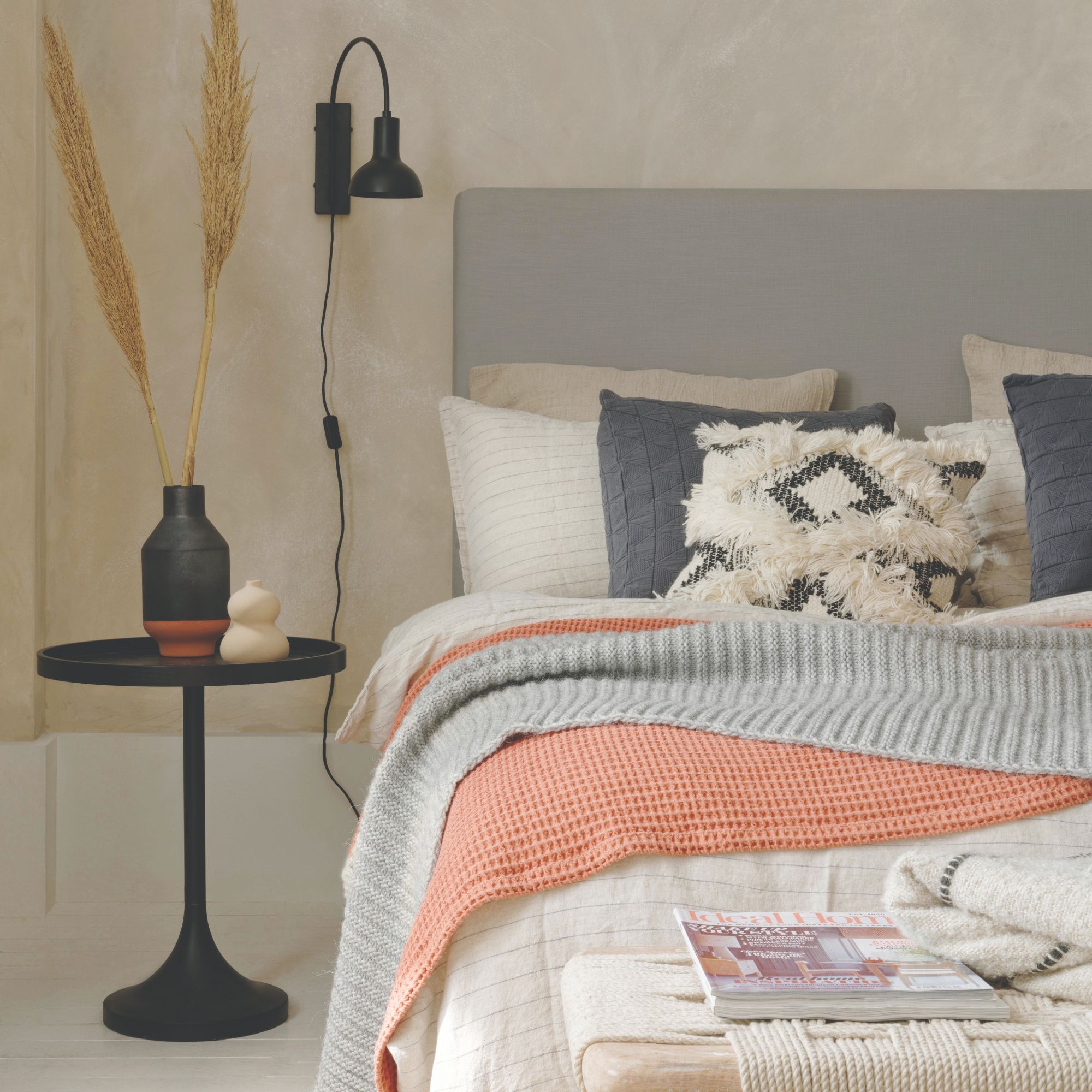 A scandi-style bedroom with layered bedding and cushions