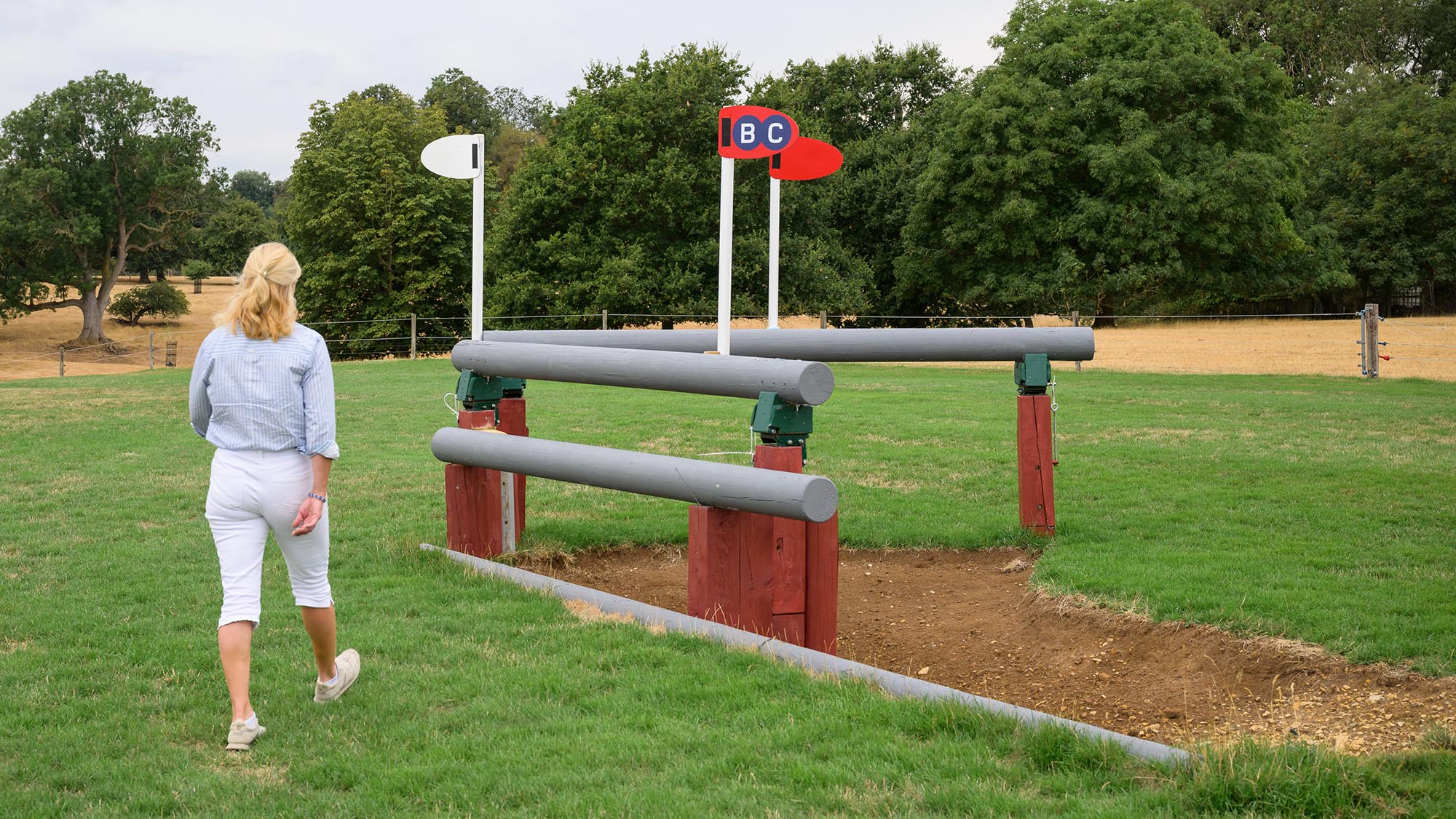 Back view of event rider Tina Cook walking up to a corner fence on the Burghley cross-country course 2026