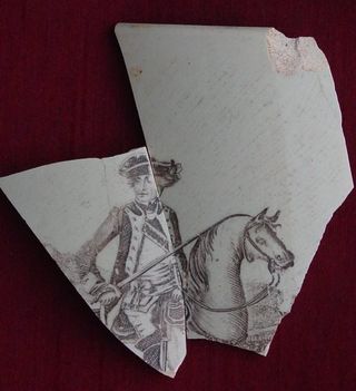 A fragment of brown, printed pearlware, a type of ceramic ware, featuring George Washington on horseback (manufactured from 1790 to 1840), was found on the grounds of City Hall.