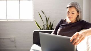 Post-menopausal woman looking at laptop screen while sitting on the sofa