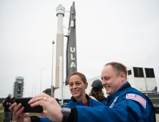 NASA astronauts Nicole Mann and Mike Fincke snap a selfie with the rocket and spacecraft of Starliner's uncrewed test vehicle before its Dec. 20, 2019, launch.