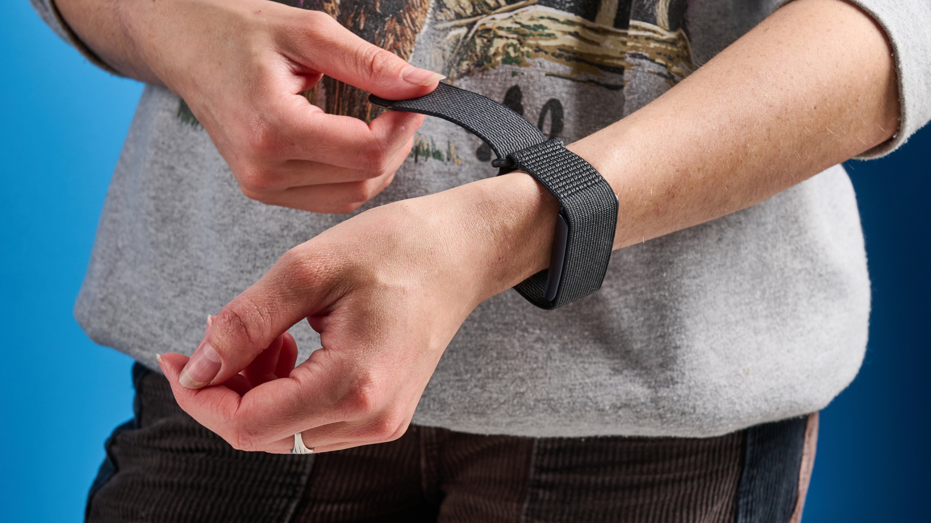 the amazfit helio strap fitness tracker with a screenless design, showing the gray strap worn around the wrist and the charger