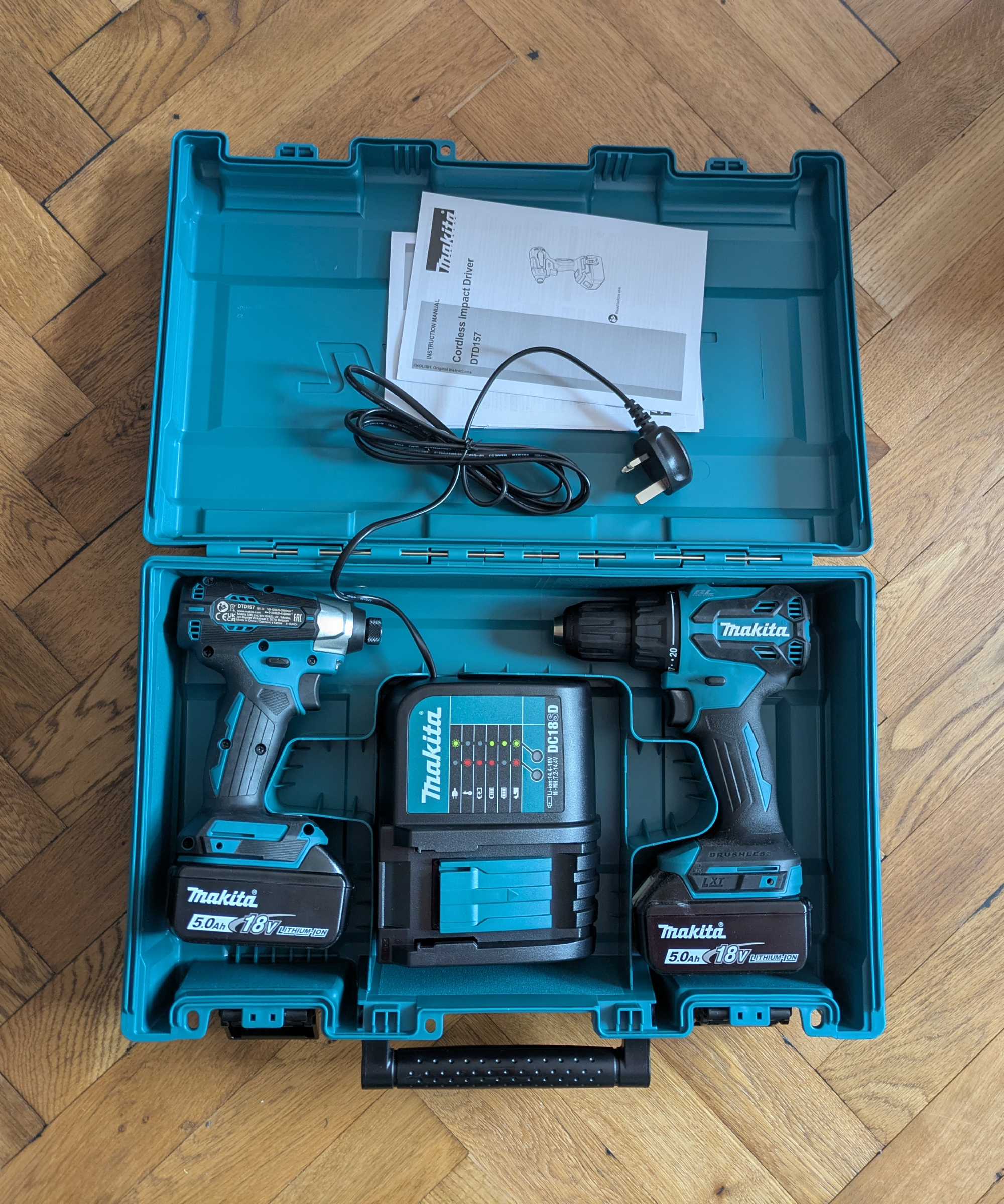 A Makita power tool box opened to show the drill, impact driver and battery charger inside it
