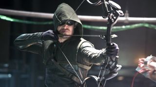 Stephen Amell suited up as The Arrow and holding bow and arrow