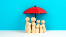 A red umbrella over a family of wooden figures against a blue background.