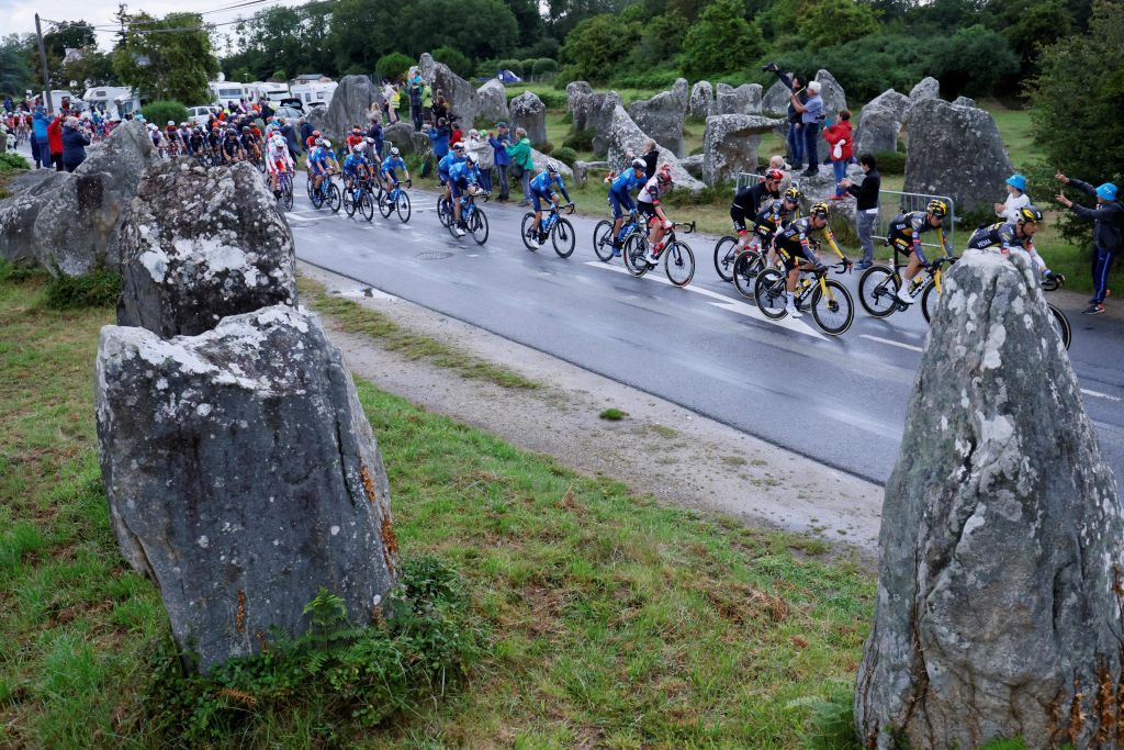 The pack rides among the Carnac megalithic stones alignments during the 3rd stage of the 108th edition of the Tour de France cycling race 182 km between Lorient and Pontivy on June 28 2021 Photo by Thomas SAMSON AFP Photo by THOMAS SAMSONAFP via Getty Images
