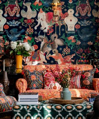 Maximalist living room with orange patterned sofa, patterned cushions, artistic mural wallpaper