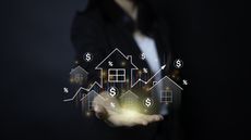 A businesswoman appears to hold digitized homes and dollar signs in her hand.
