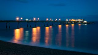 Image shows a beach and pier at night taken with the 3 Legged Thing PUNKS Brian Tripod.