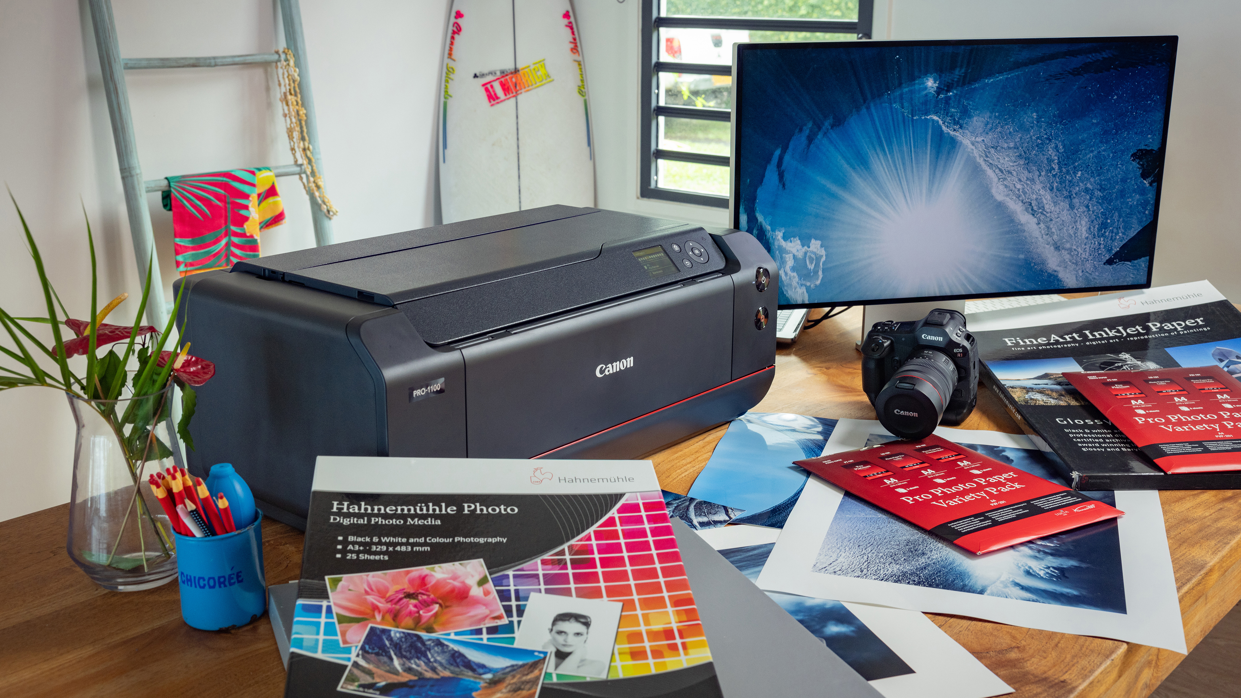 Canon ImagePrograf Pro-1100 on a desk, in a home studio, next to a Canon camera, a computer monitor and printed photos