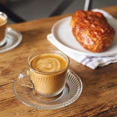 Two cups of coffee with pastries on a wooden dining table