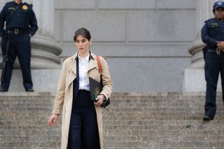 lizzy caplan wearing a trench coat walking down steps of a government building in zero day