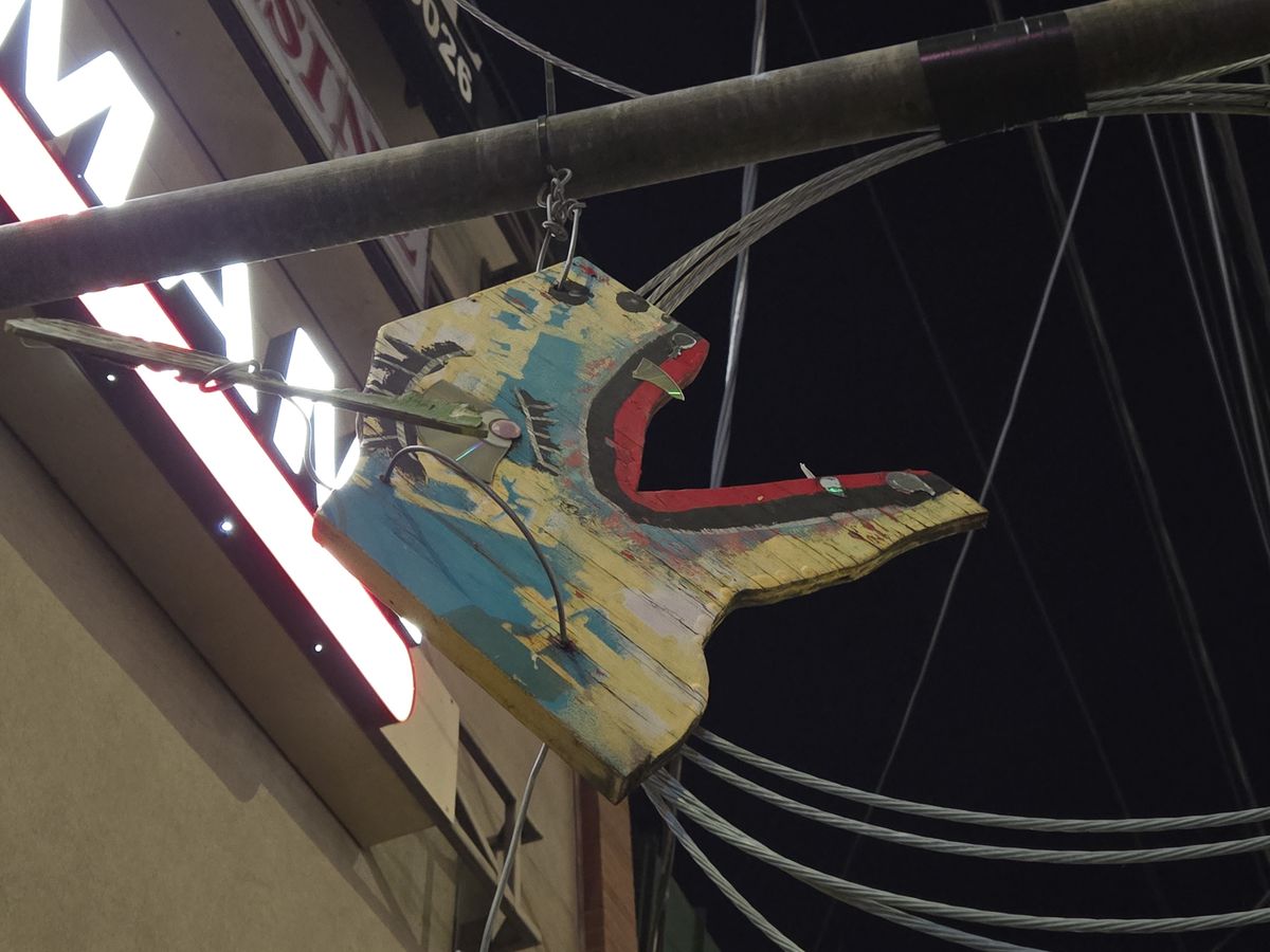 A wooden carving of an animal face hanging from a pole
