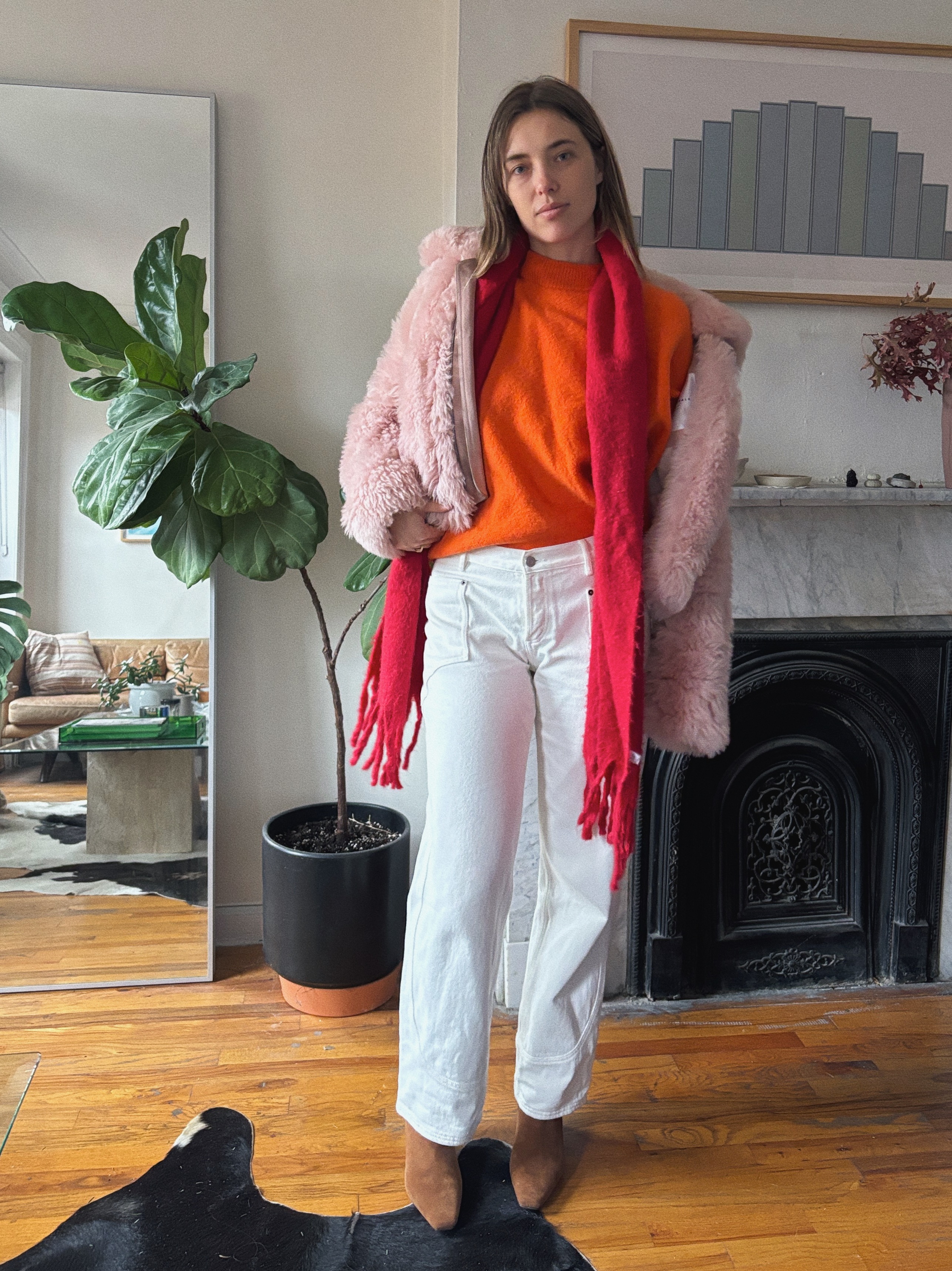 Aemilia Madden wearing an orange top, a pink coat, and white pants