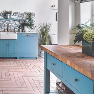 Kitchen with light blue cabinetry and blue freestanding kitchen island with wood worktop.