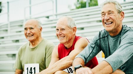 Laughing senior male athletes hanging out together on bleachers 