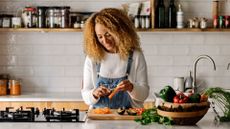 Woman chopping vegetables on a board in the sunshine with smile, representing methods for weight loss in menopause