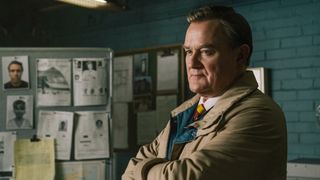 Boyce stands with his arms crossed in The Gold season 2