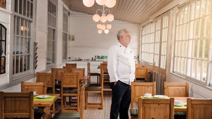 A restaurant owner stands among empty tables.