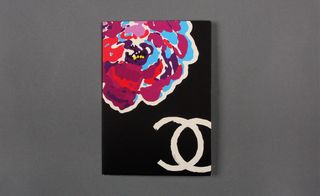 Front view of ﻿Chanel's black and white invitation featuring a multicoloured flower pictured against a grey background