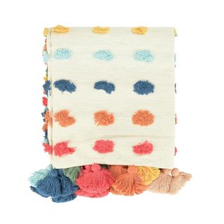 A white throw with colorful spots and tassels