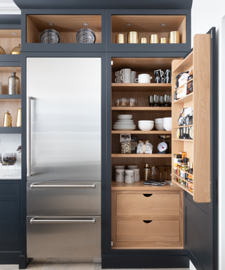 Dark kitchen cabinets with organized internal storage next to a refrigerator