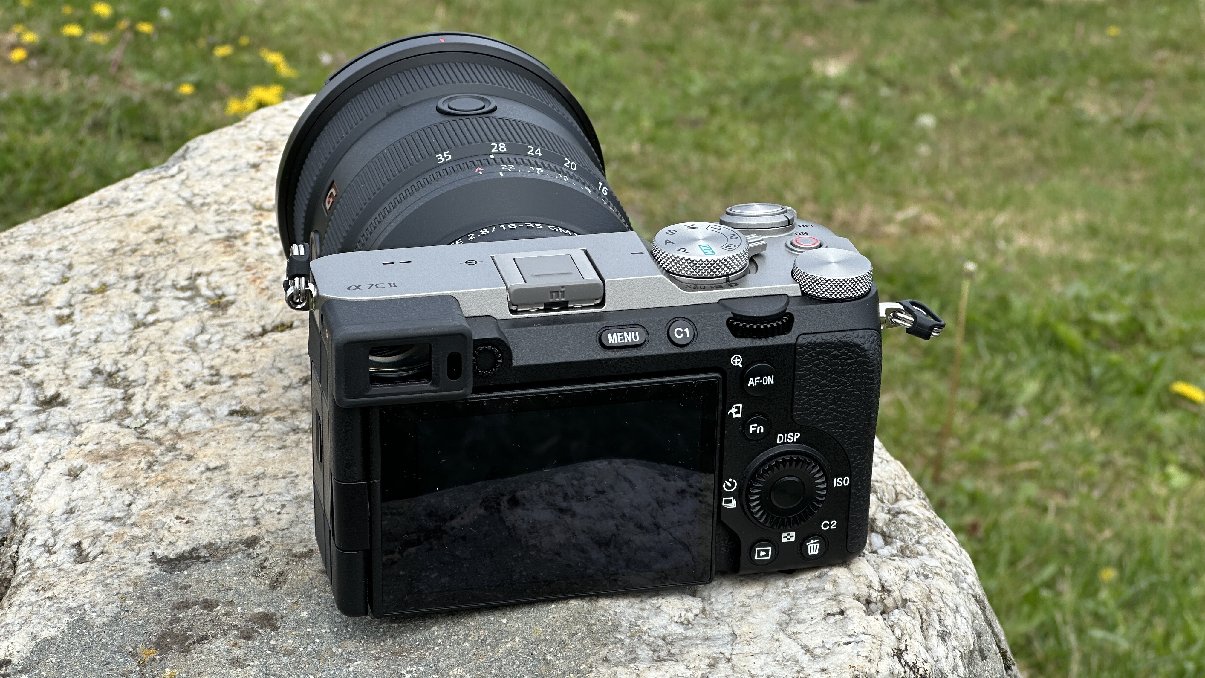 Rear of Sony A7C II mirrorless camera outside on a rock with Sony FE 16-35mm F2.8 GM II lens attached
