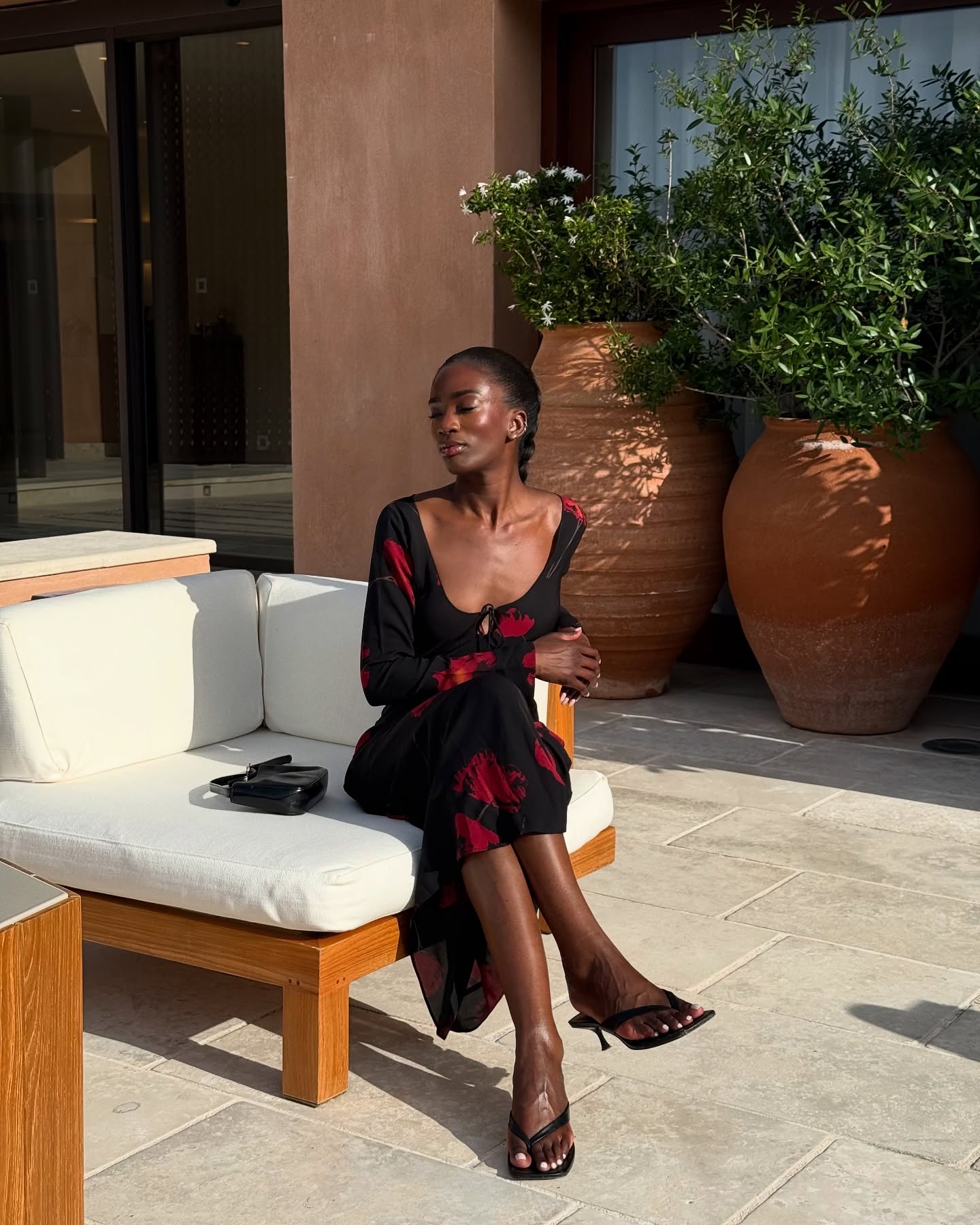 An image of @_livmadeline wearing a black and red floral mini dress with heeled flip flops.