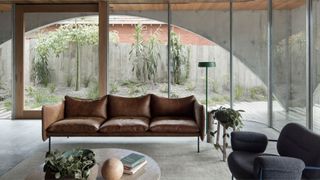 A home with houseplants scattered around and a leather sofa with an accent chair