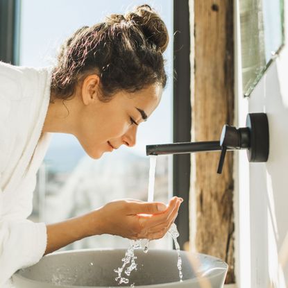 woman washing her face in a sink