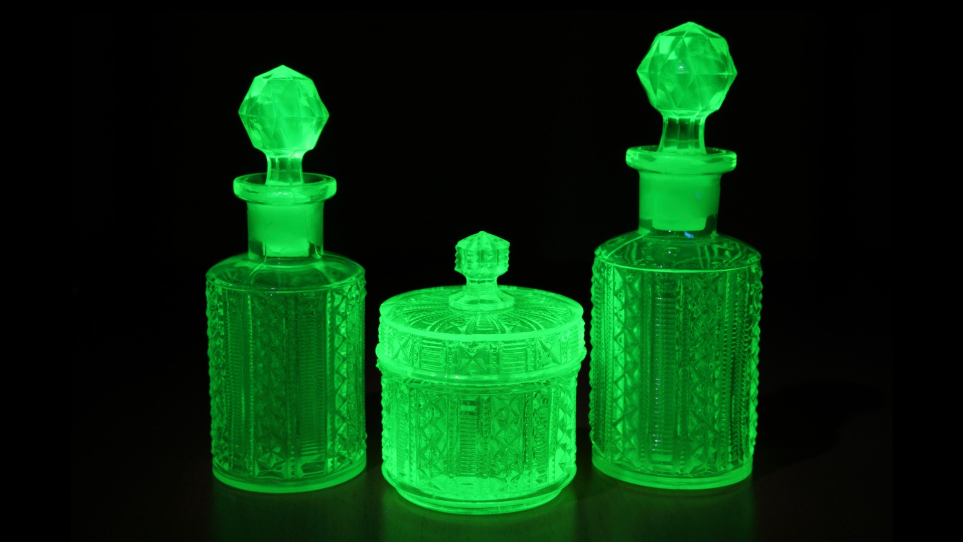 Art deco molded green uranium glass lit by UV light on a table. The uranium glows green with fluorescence._Peter Chow UK via Shutterstock