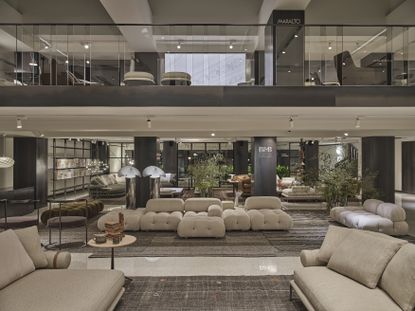 D Studio Milano showroom space with two floors visible displaying furniture. Camaleonda sofa by Mario Bellini in white is visible at the centre