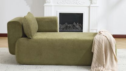 Moss green boneless chaise lounge pictured in an all-white living room with an antique fireplace