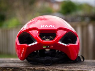 A red Kask Utopia Y aero helmet sits on a wooden bench